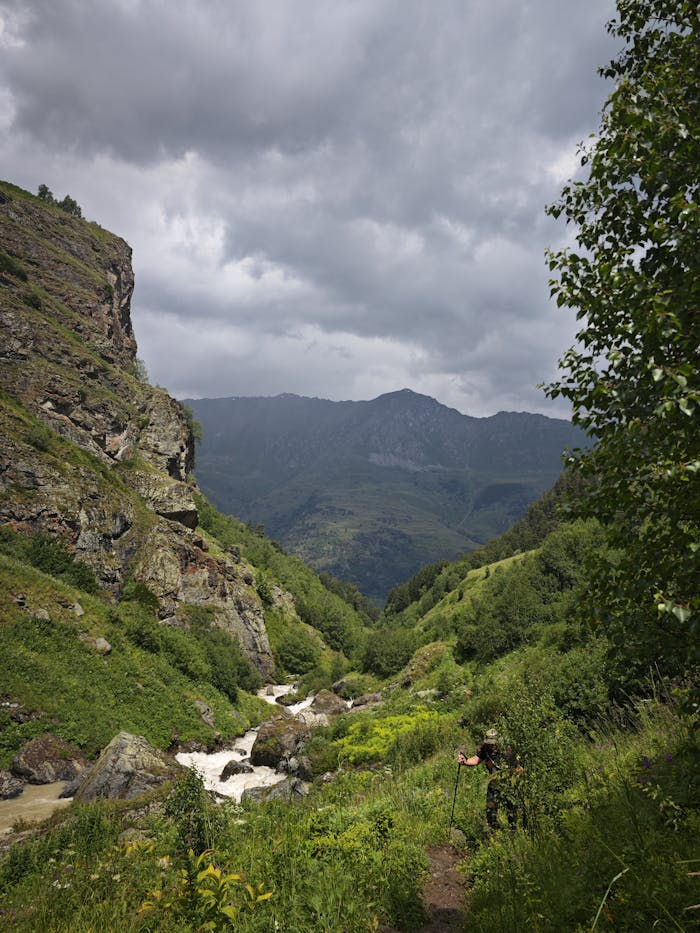 Explore a dramatic mountain landscape with lush greenery and rocky cliffs.