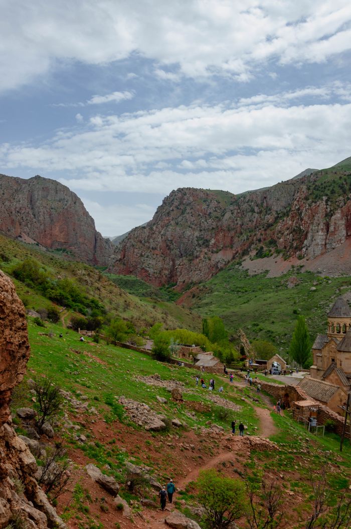 A breathtaking view of Noravank Monastery nestled among stunning red rock cliffs and lush green landscape.